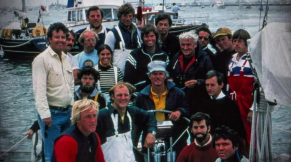Vintage crew photo aboard a sailboat in a crowded harbor