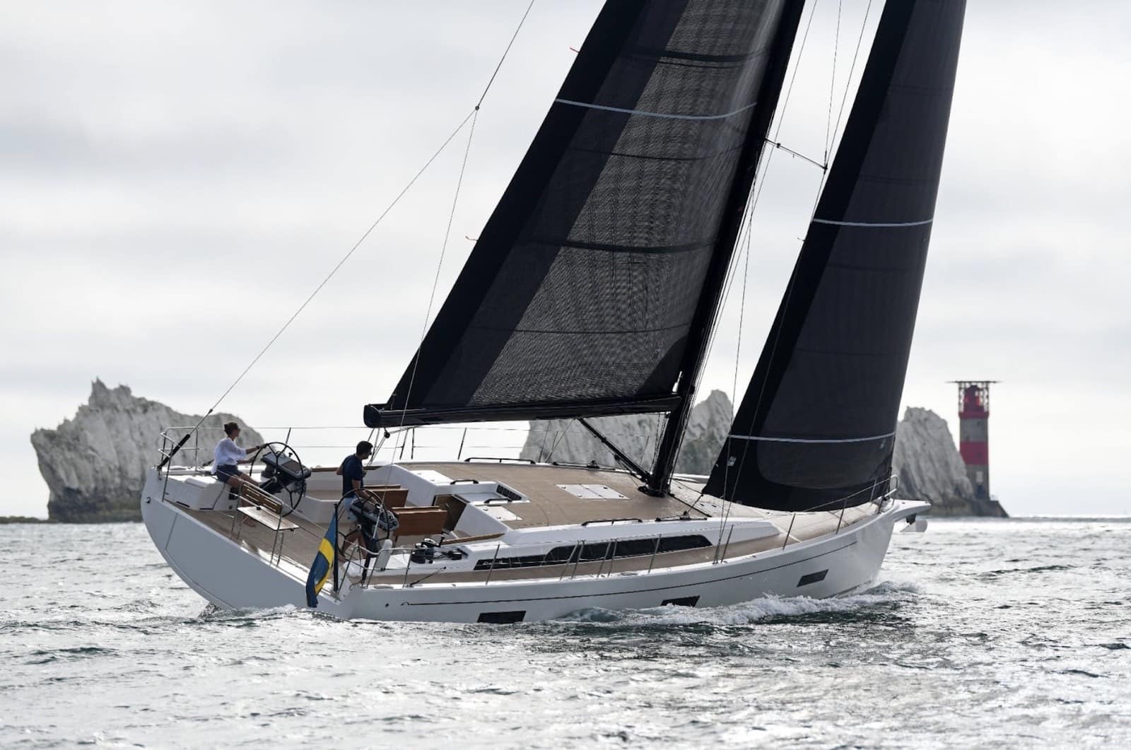 Arcona 50 heeled under black X-Drive® sails past a rock arch and lighthouse