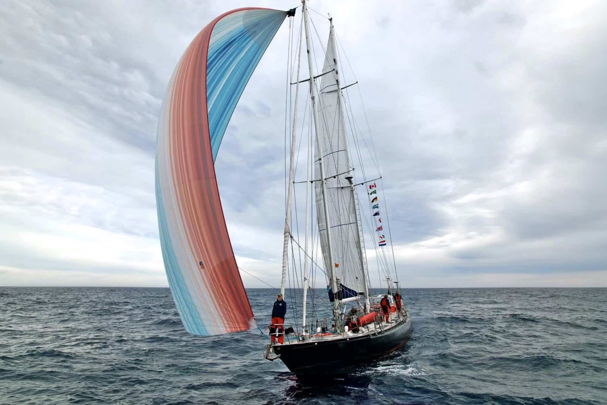 Schooner ABEL TASMAN sails under a striped spinnaker through the Northwest Passage, once icebound.
