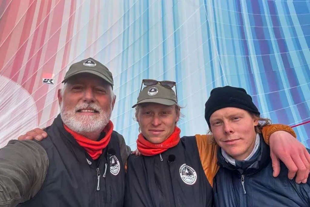 Expedition leader Keith Tuffley poses with ABEL TASMAN skipper, Isak Rockström, and first mate, Alex Rockström, in front of the Climate Stripes Gennaker. Photo Ⓒ Ocean Science Expedition.