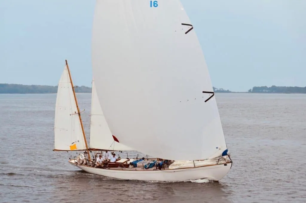 Classic gaff-rigged yawl 16 sails downwind under full white sails on calm water.