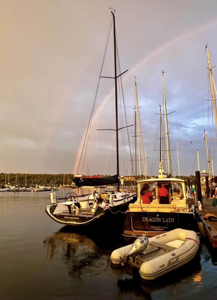 Classic yacht DRAGON LADY moored at dusk with a rainbow arching over the harbor.