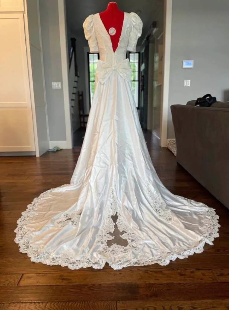 Ivory sailcloth wedding gown with puffed sleeves, a bow, and a lace-trimmed train, shown from behind.