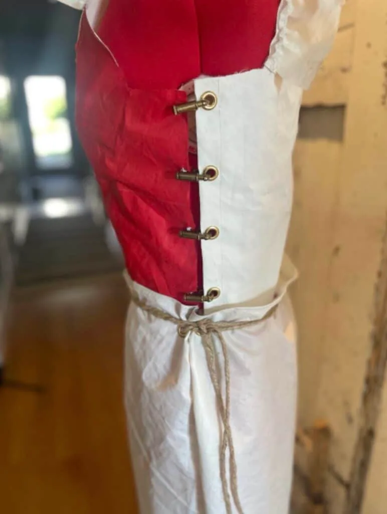 Close-up of a sailcloth dress bodice closed with brass grommets and laced cord.