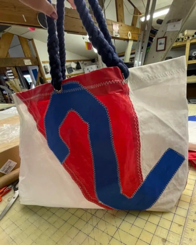 Recycled sailcloth tote bag with a blue zigzag appliqué and braided navy rope handles.