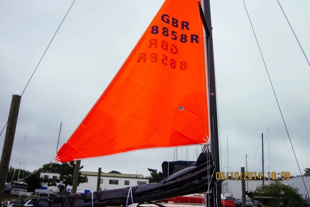 A bright orange storm trysail set behind the mast