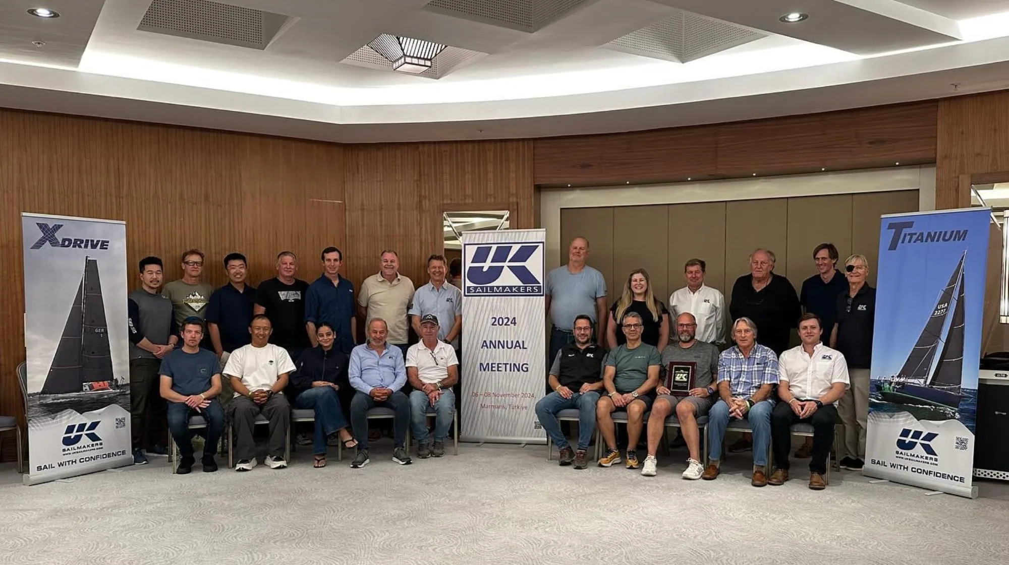 UK Sailmakers staff group photo at the 2024 Annual Meeting, X-Drive® and Titanium banners behind