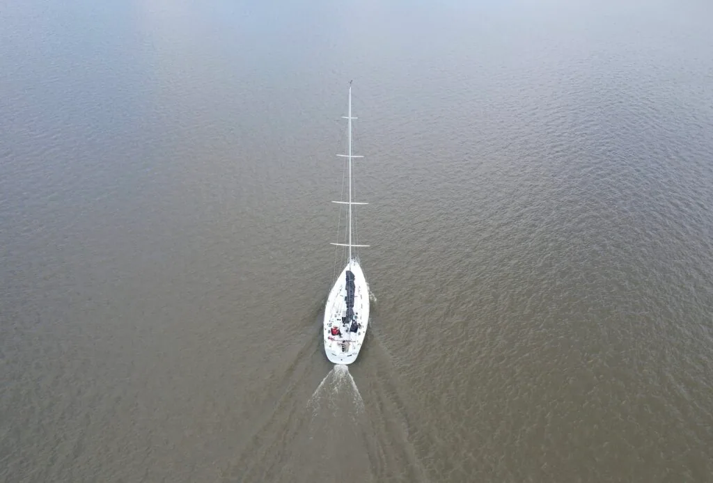 Aerial view straight down on SOULMATES motoring across calm brown water