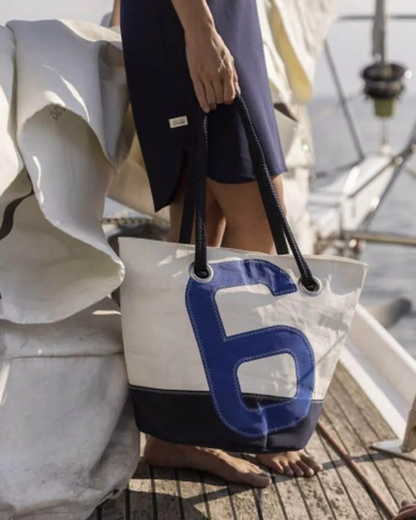 Tote bag made from recycled sailcloth with a blue number six, carried on deck