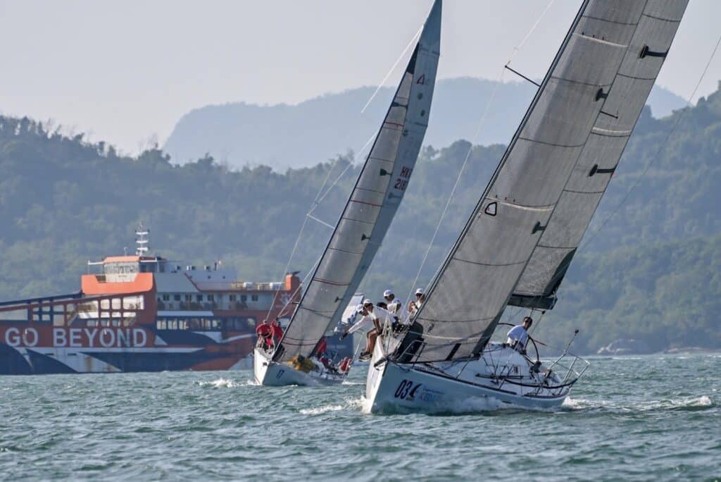 Two racing yachts close together off Langkawi, a large ferry behind