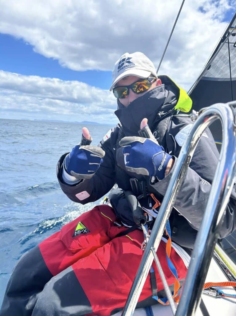Sailor at the helm giving a thumbs-up during the Sydney Hobart race