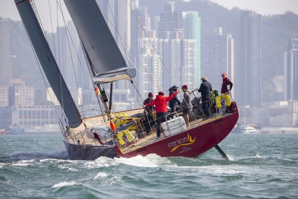 FENICE heeled hard with crew hiking out, Hong Kong skyline behind