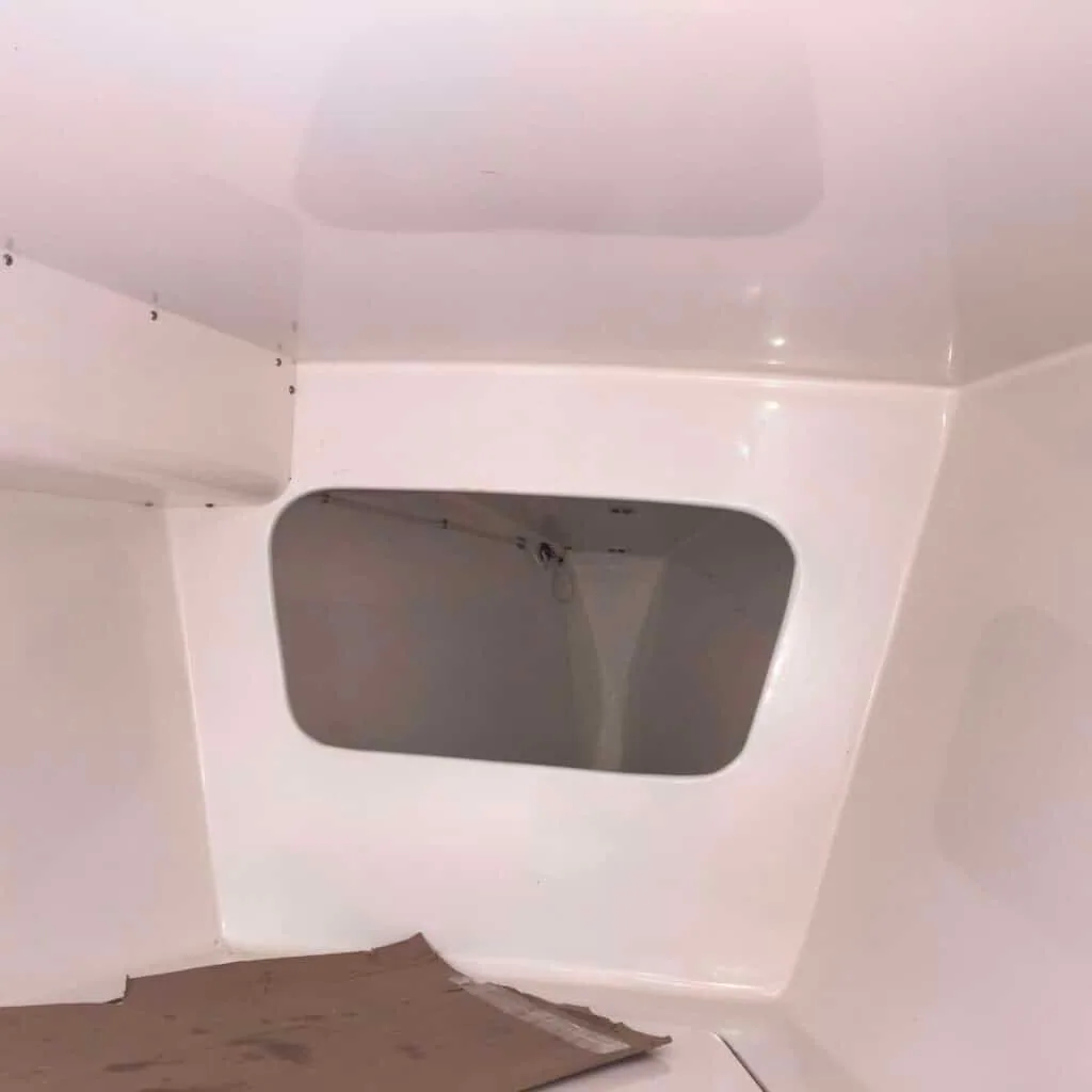 White fiberglass interior bulkhead with a dark hatch cutout during a cruising-yacht refit