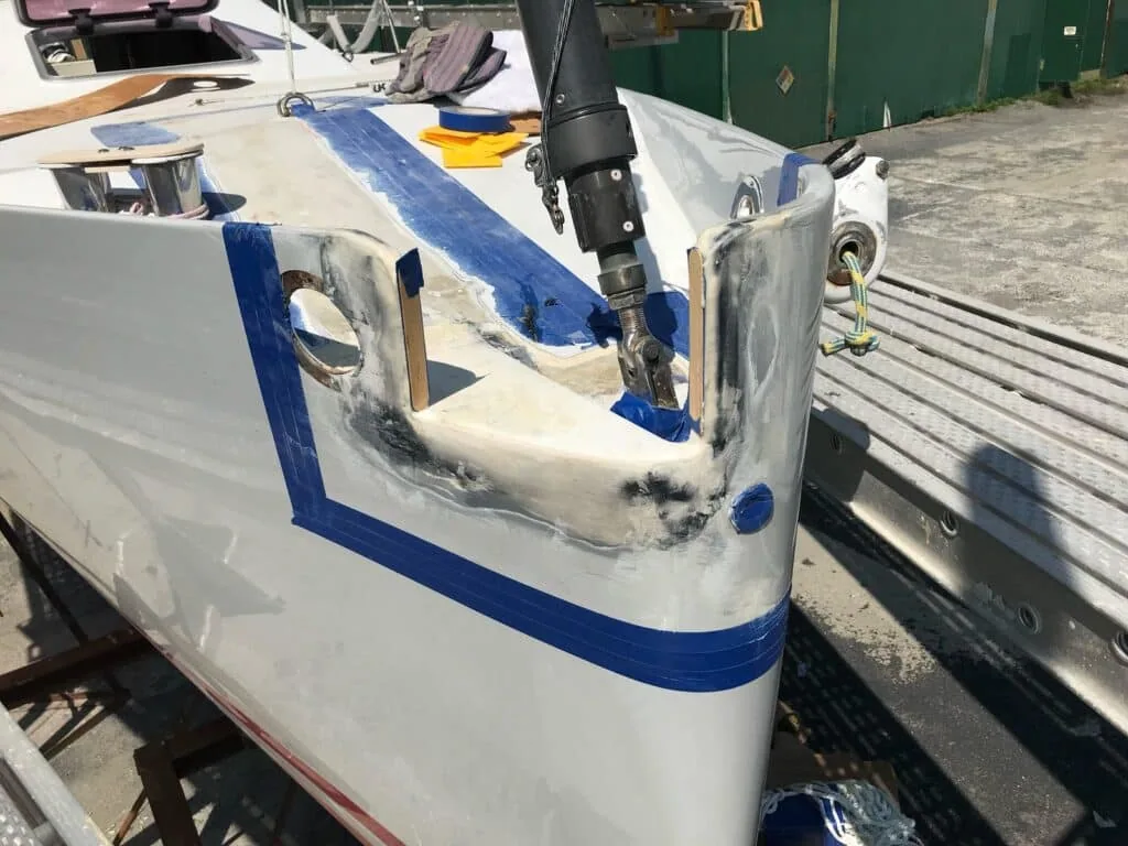 Boat bow on stands with a new fitting bedded in, blue tape marking the boot stripe