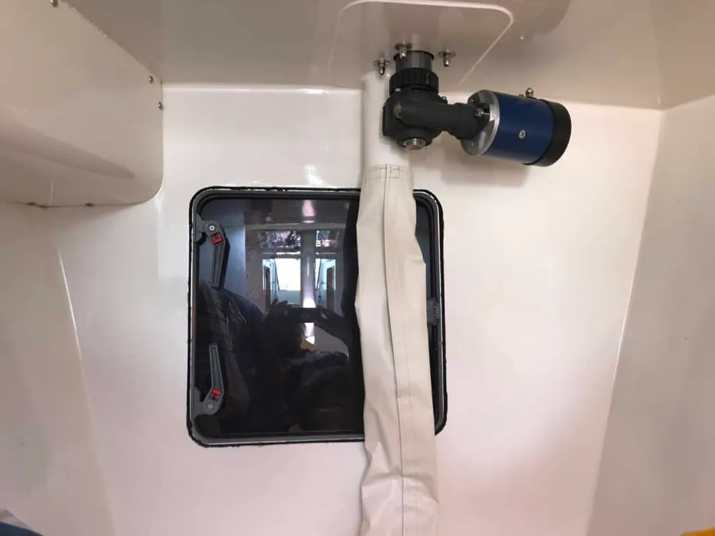 Finished white crash bulkhead with a small hatch and windlass motor mounted through it
