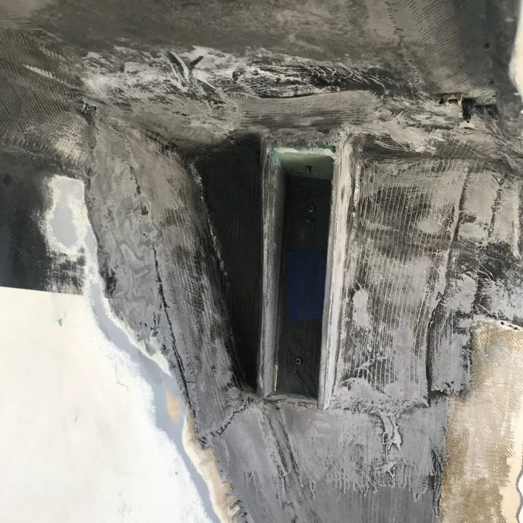 Raw fiberglass layup around a new chainplate reinforcement, mid-construction