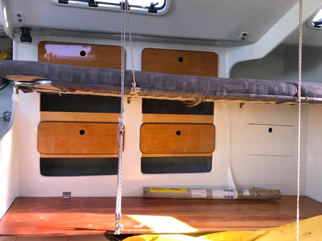 Port-side salon lockers with teak-faced doors and a sail bag stowed overhead