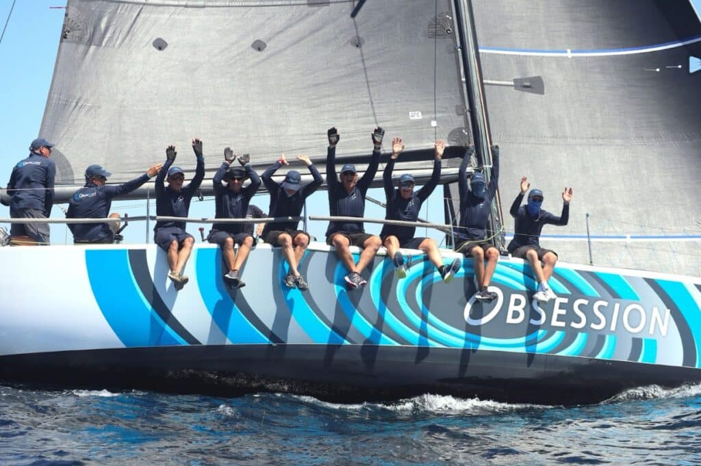 OBSESSION crew raising their arms in celebration on the rail at Geographe Bay Race Week