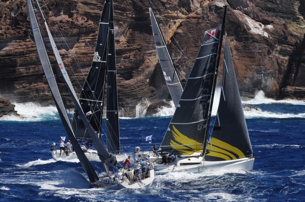 Pogo 12.5 HERMES among the fleet at the start of the windy RORC Caribbean 600 along a rocky coast