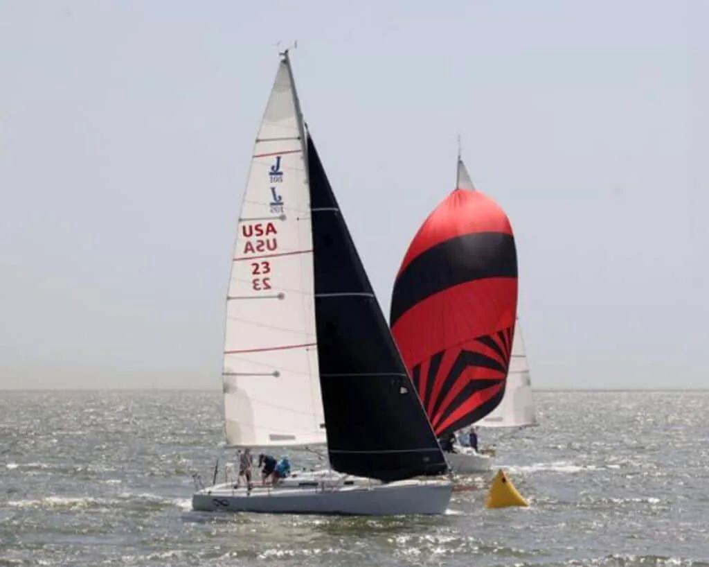 J/105 sail number 23 flying a red-and-black spinnaker while rounding a mark
