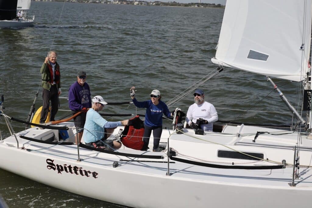 Crew aboard SPITFIRE hoisting a small white spinnaker during the J/105 Invitational