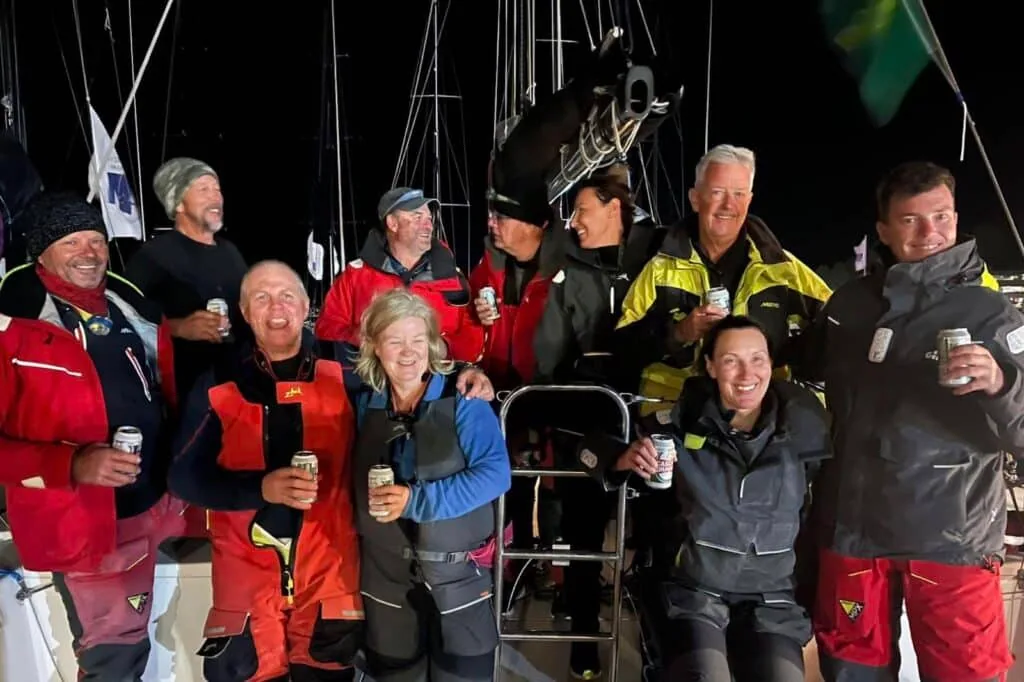 Sailing crew celebrating with drinks on deck at night after finishing the Sydney Hobart