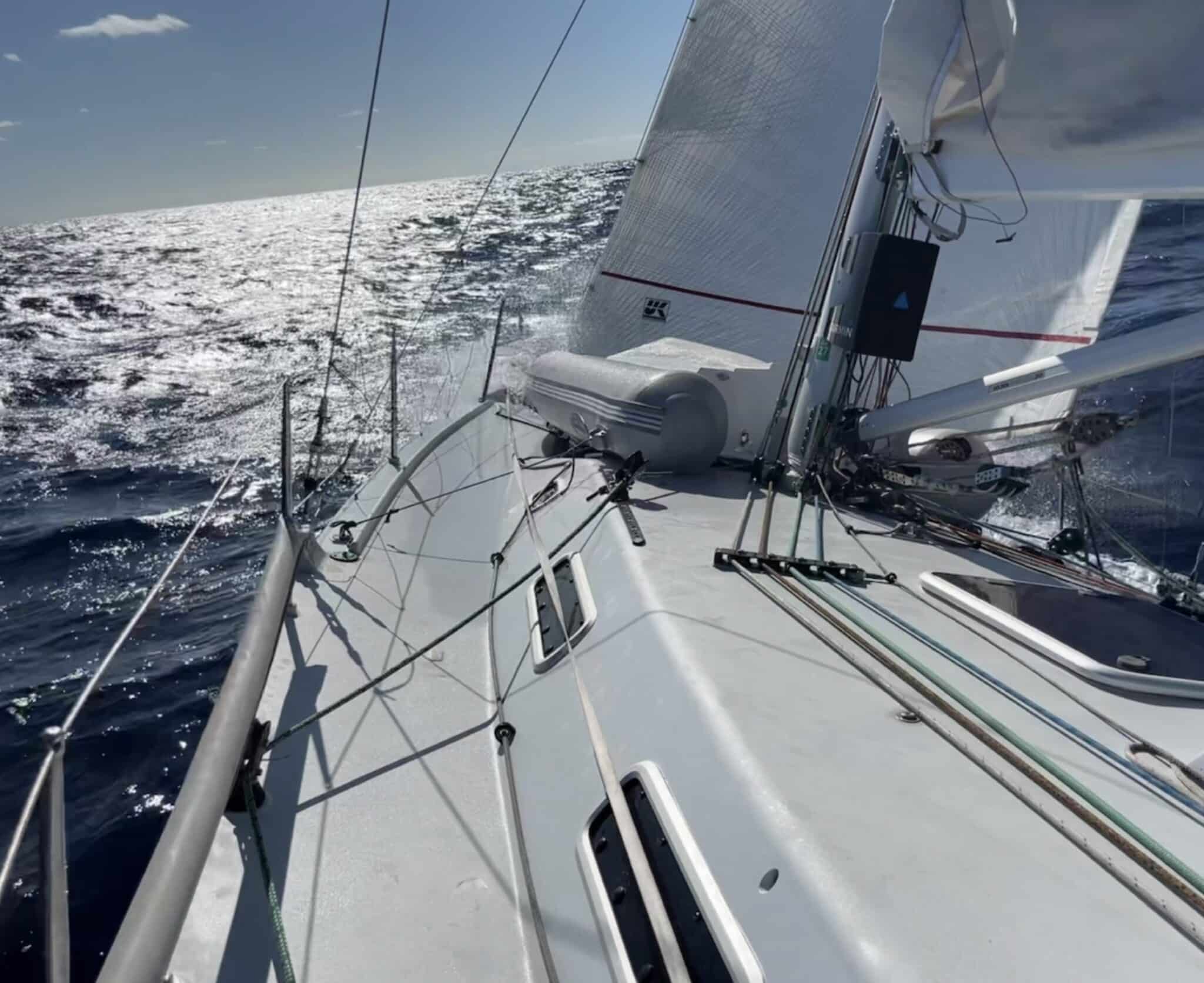 Sailing offshore in bright sun with an inflatable dinghy lashed on deck