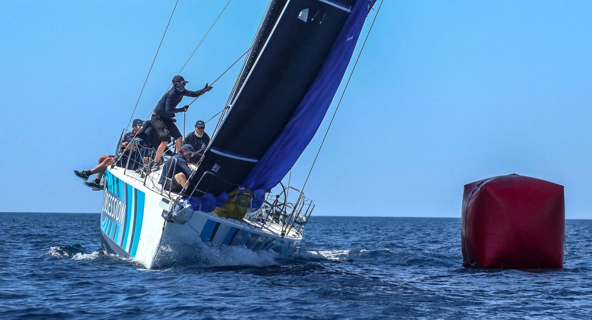 OBSESSION rounding a mark with a dark jib set and crew hiked out to windward