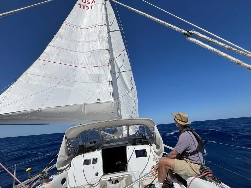 Adam Loory at the helm trimming the headsail aboard USA 1131 on a sunny reach