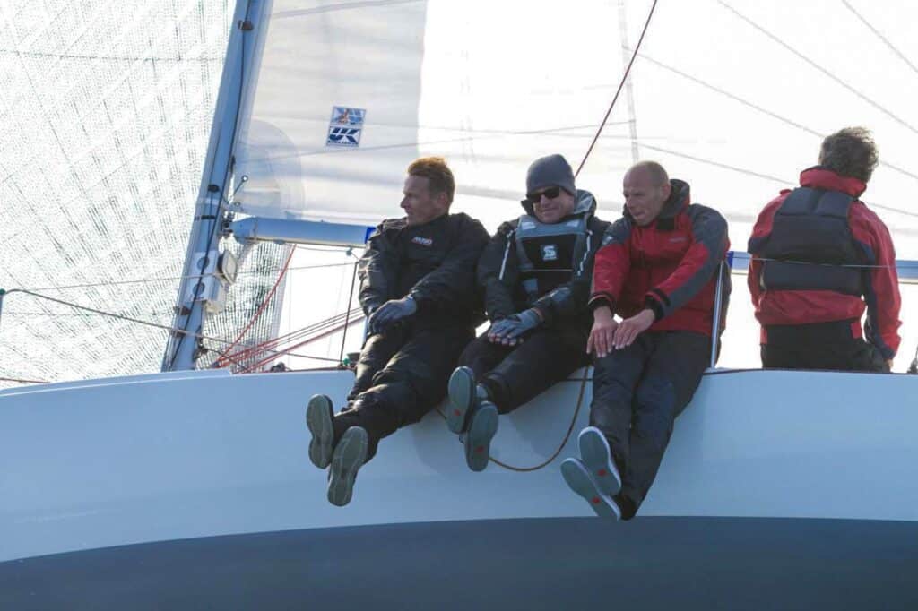 Four crew members hiking out on the rail of a racing sailboat
