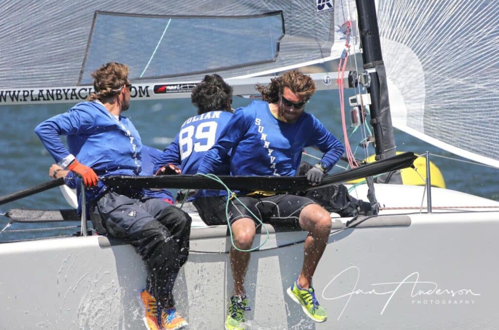 Skiff crew hikes out hard, bib number 89 named Julian, spray off the hull