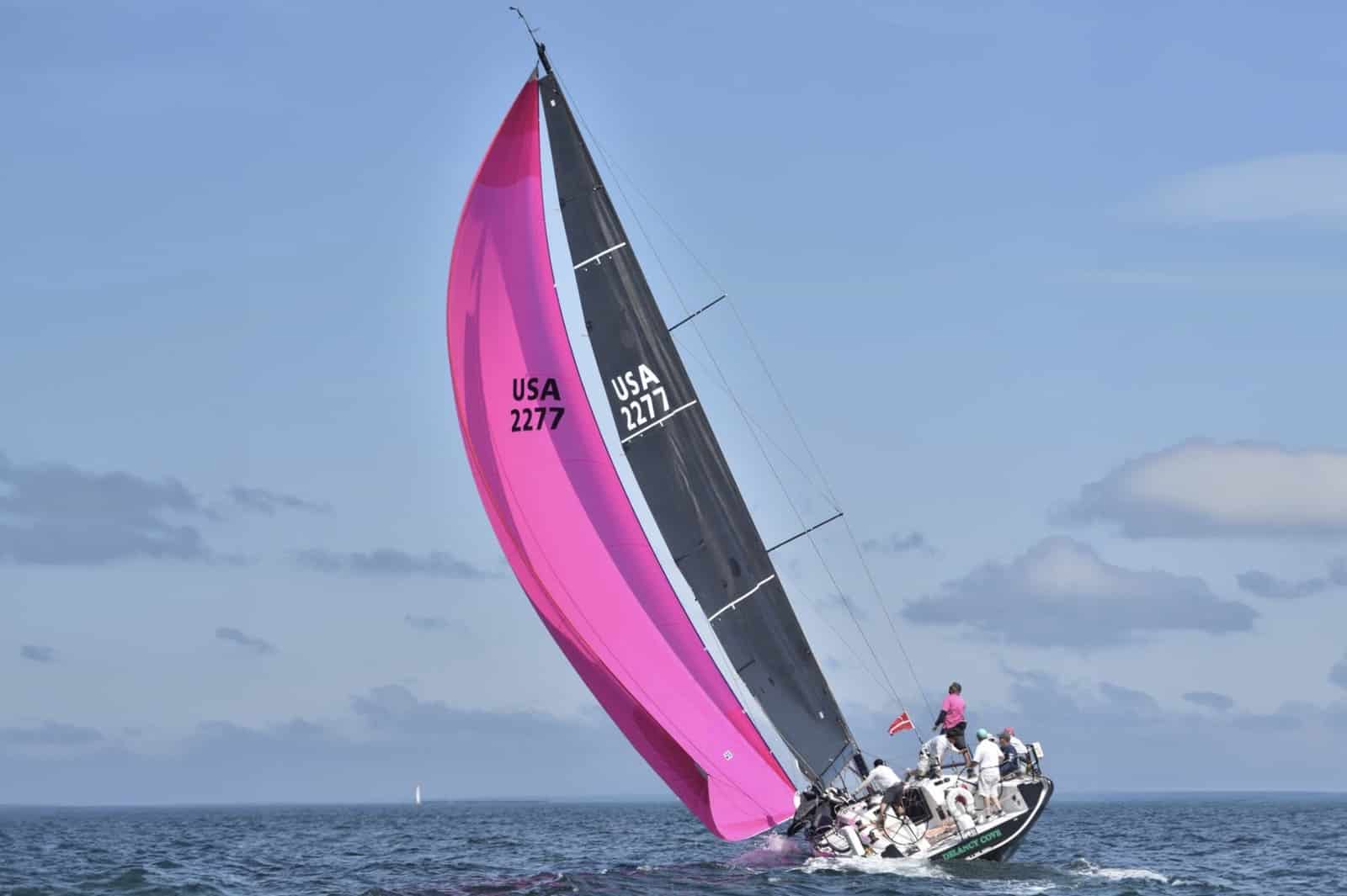 Pink and black reaching spinnaker filled on USA 2277 under a blue sky