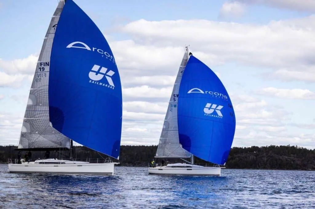 Two Arcona yachts flying matching blue UK Sailmakers spinnakers