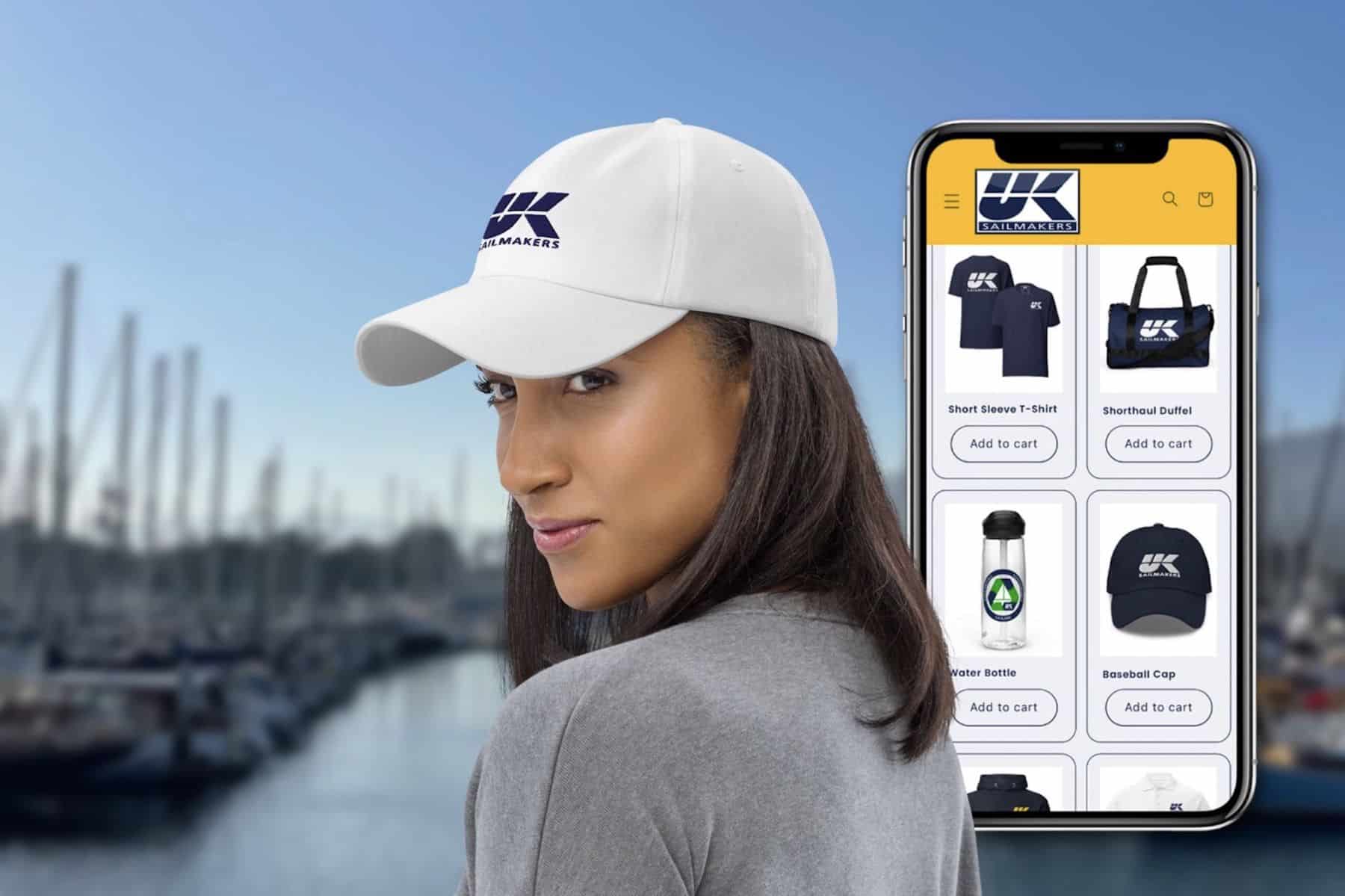 Woman in a UK Sailmakers cap beside a phone screen of the online store