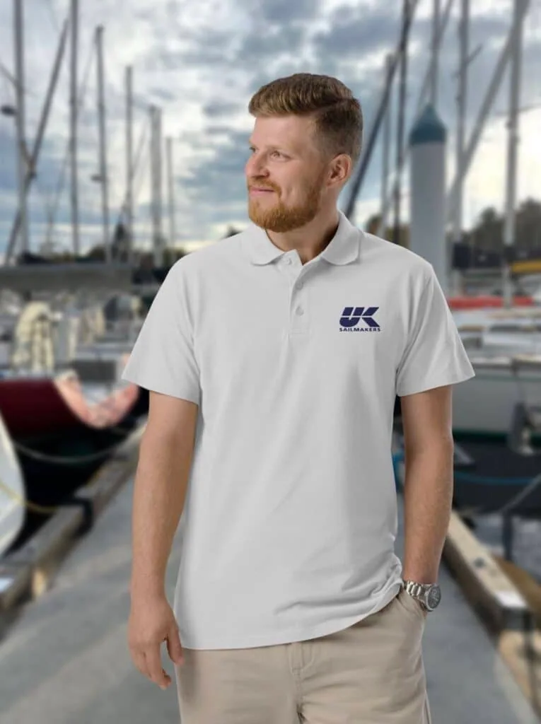 Man wearing a white UK Sailmakers logo polo shirt at a marina