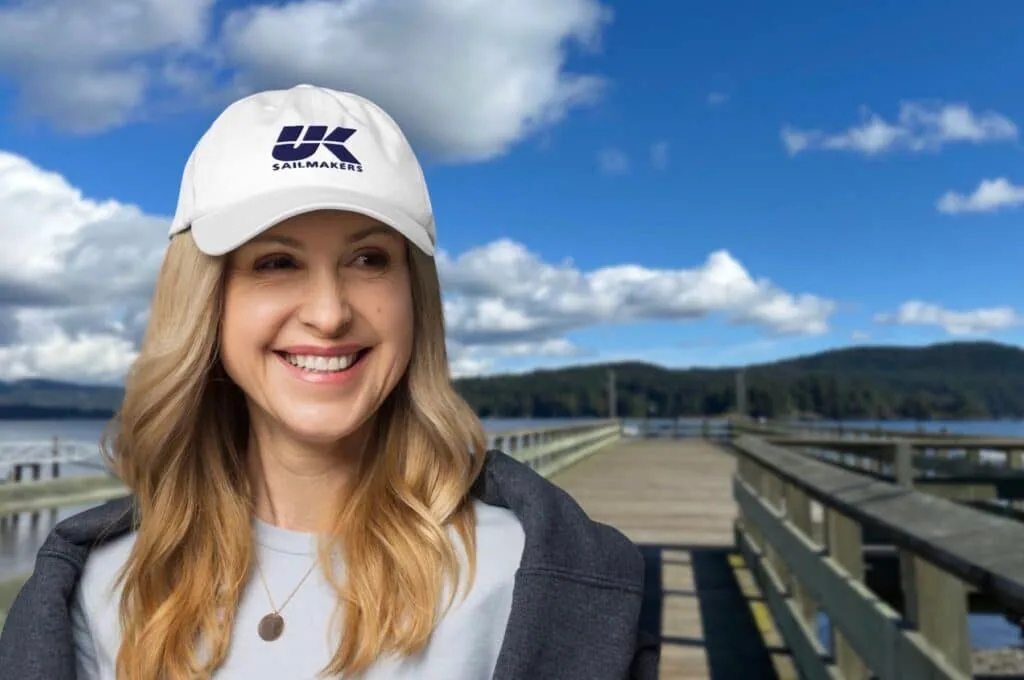 Woman wearing a white UK Sailmakers cap on a wooden pier