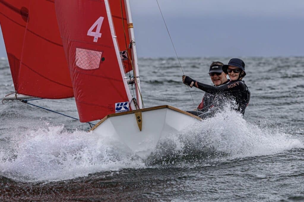 Paul and Polly Changuion charge downwind on Mirror 4 under a red sail