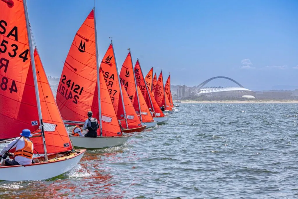 Fleet of red-sailed Mirrors on the startline, Moses Mabhida Stadium behind