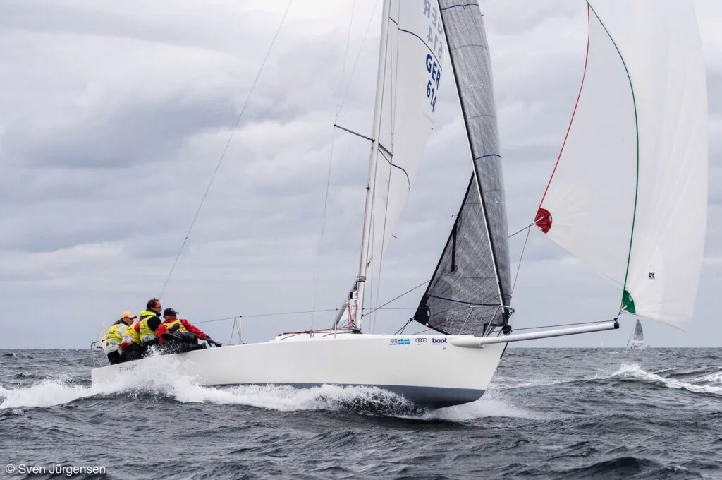 German-flagged keelboat crew hikes out hard, spinnaker still in its sock
