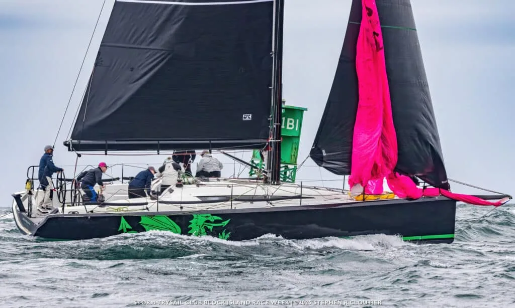 Black-hulled racer with a green dragon graphic douses its pink spinnaker