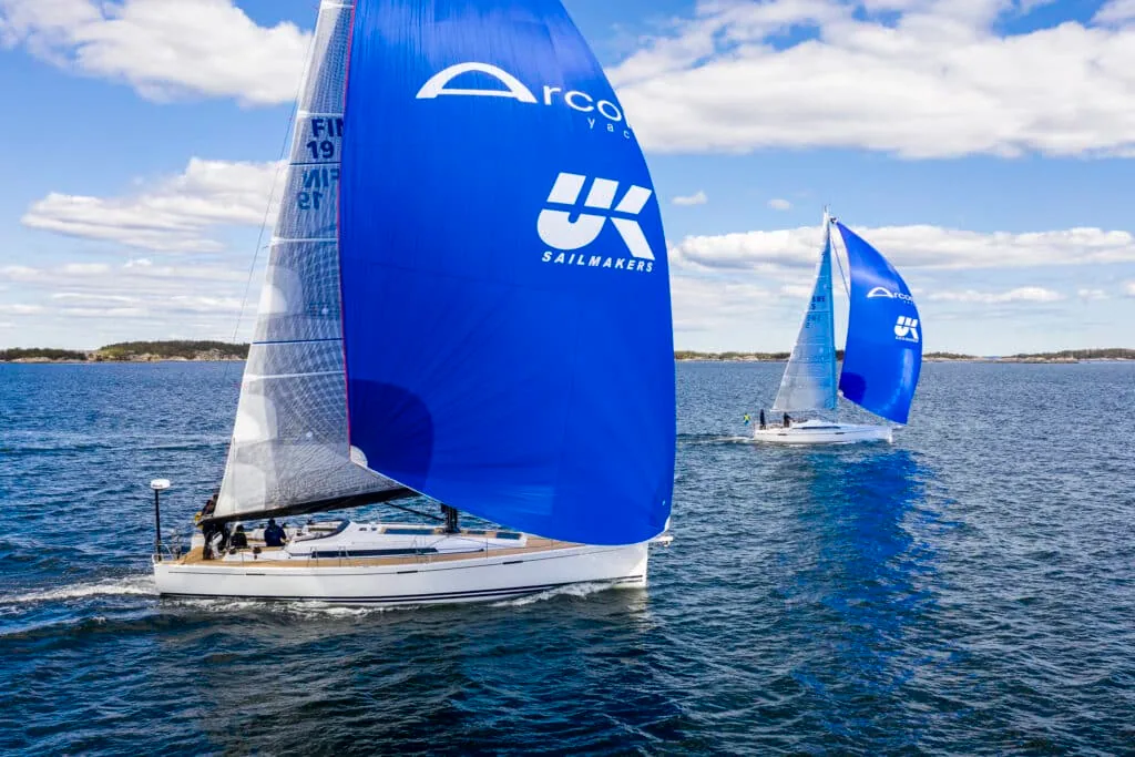 Two Arcona yachts racing under blue asymmetric spinnakers printed with UK Sailmakers branding