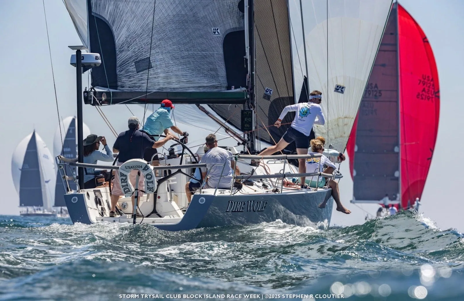 Dire Wolf's crew trims upwind as a red spinnaker is set astern