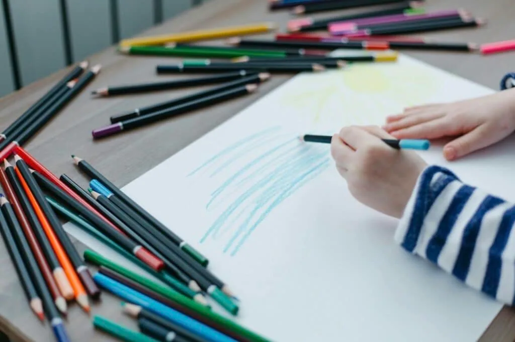 Child sketches clouds with colored pencils for the youth design contest