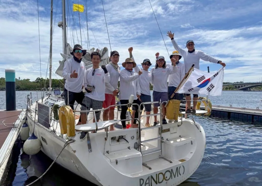 Offshore race crew celebrates dockside holding a Korean flag
