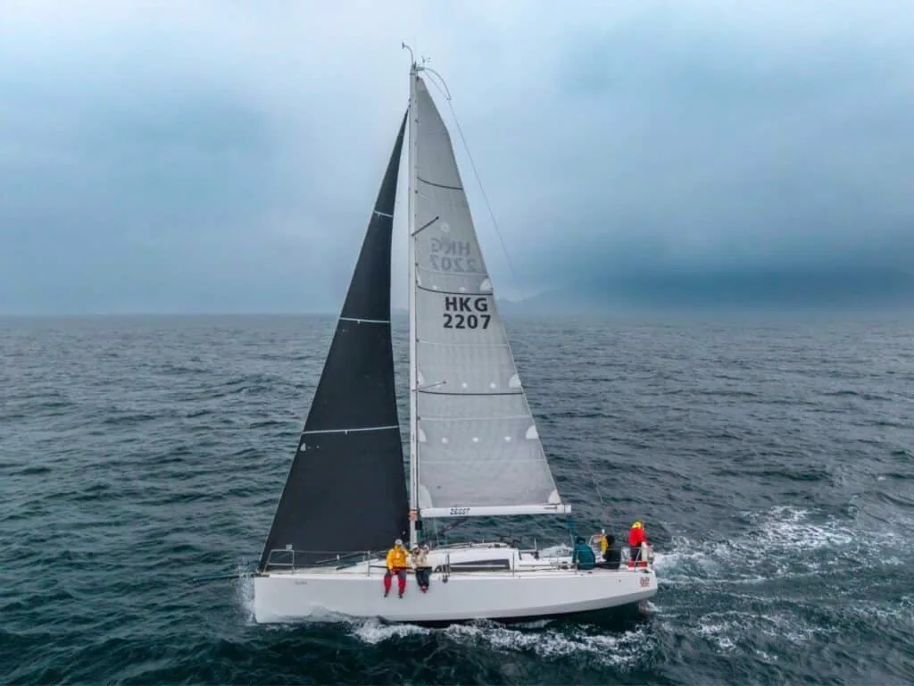 Yacht HKG 2207 racing offshore under a dark mainsail and striped genoa in fog