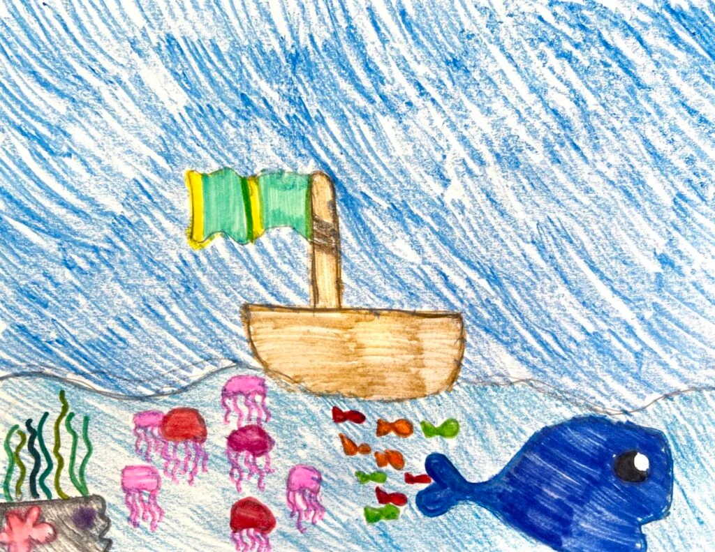 Crayon drawing of a boat with a flag sailing over jellyfish, fish, and a whale