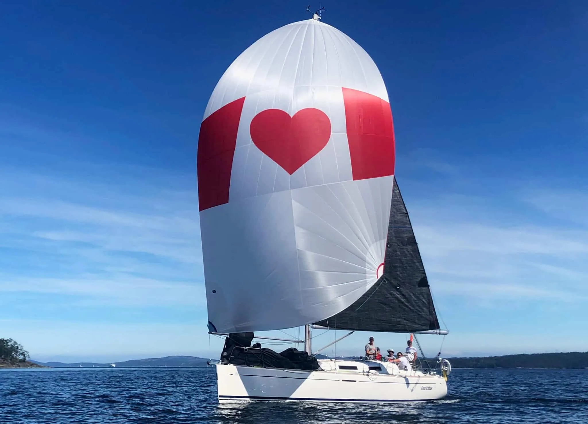 Dufour 34 cruiser flying a white spinnaker printed with a red heart
