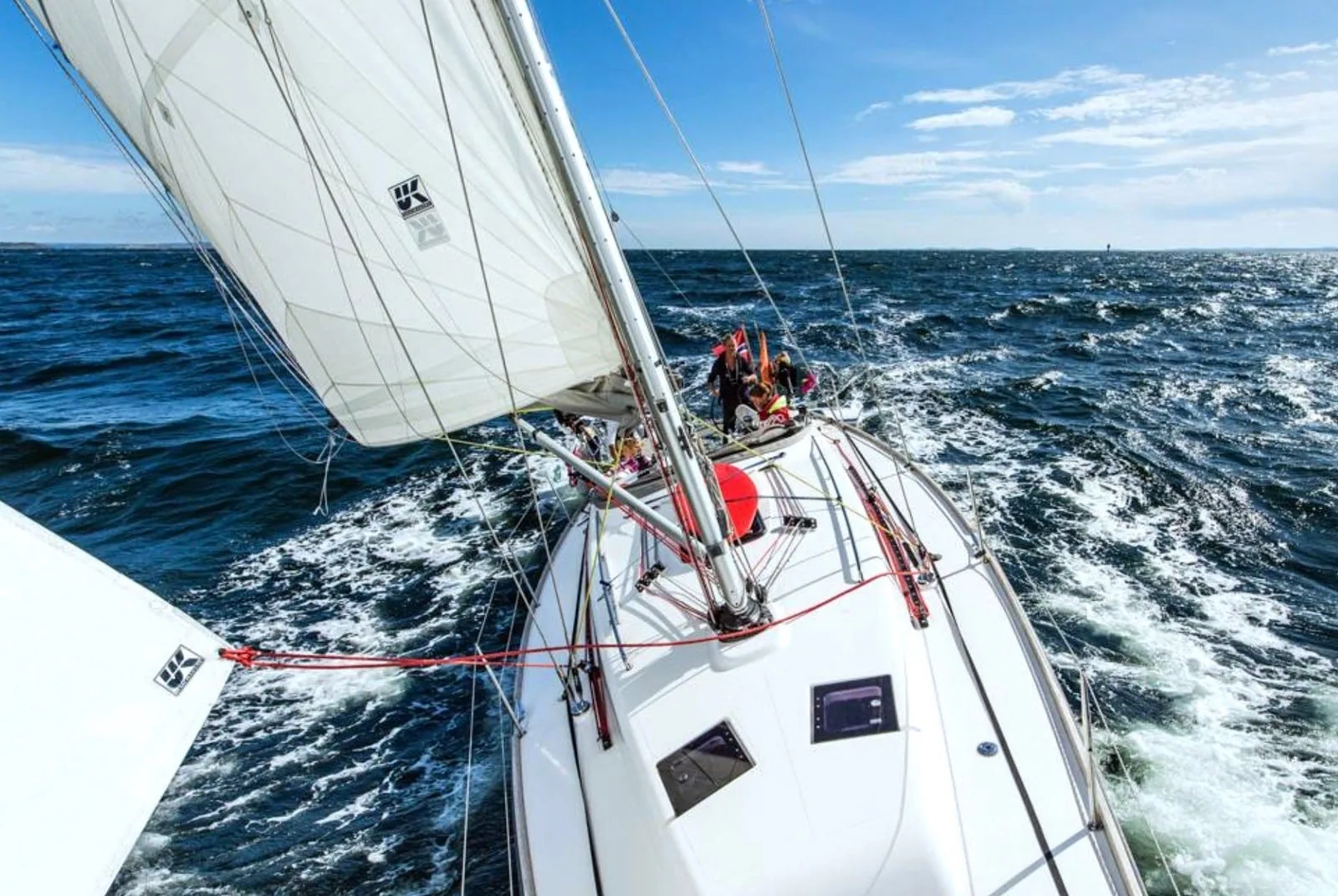 Cruising sailboat bow view heeled hard with genoa filled and a red preventer line rigged