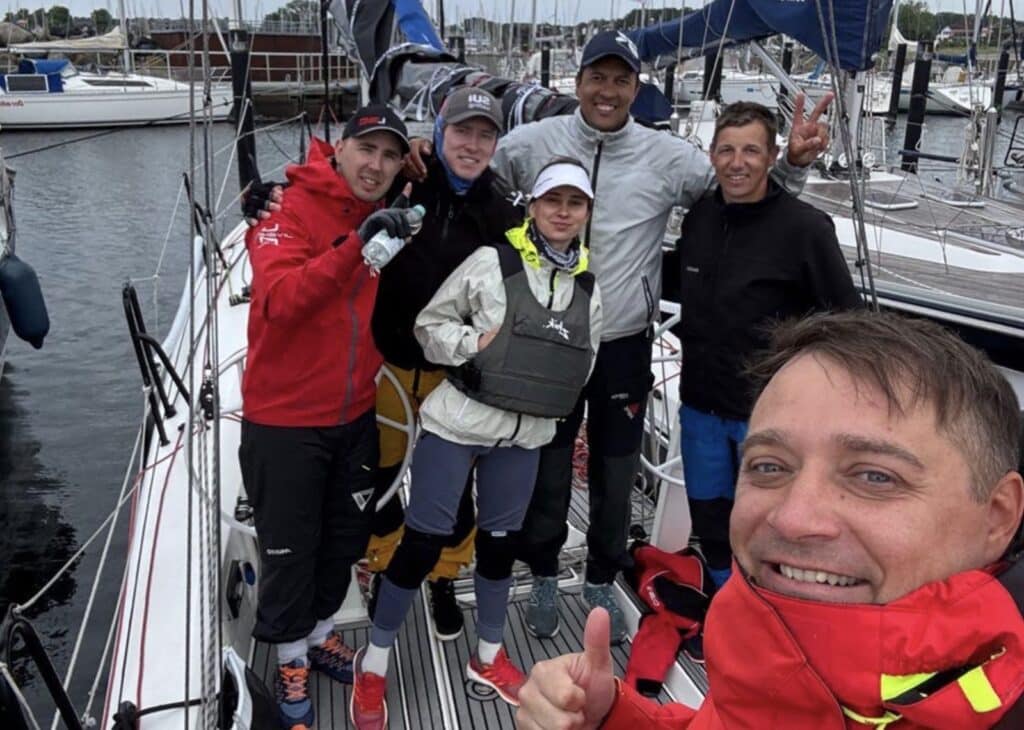 L30 keelboat heeled hard with crew hiking behind a mesh-window jib