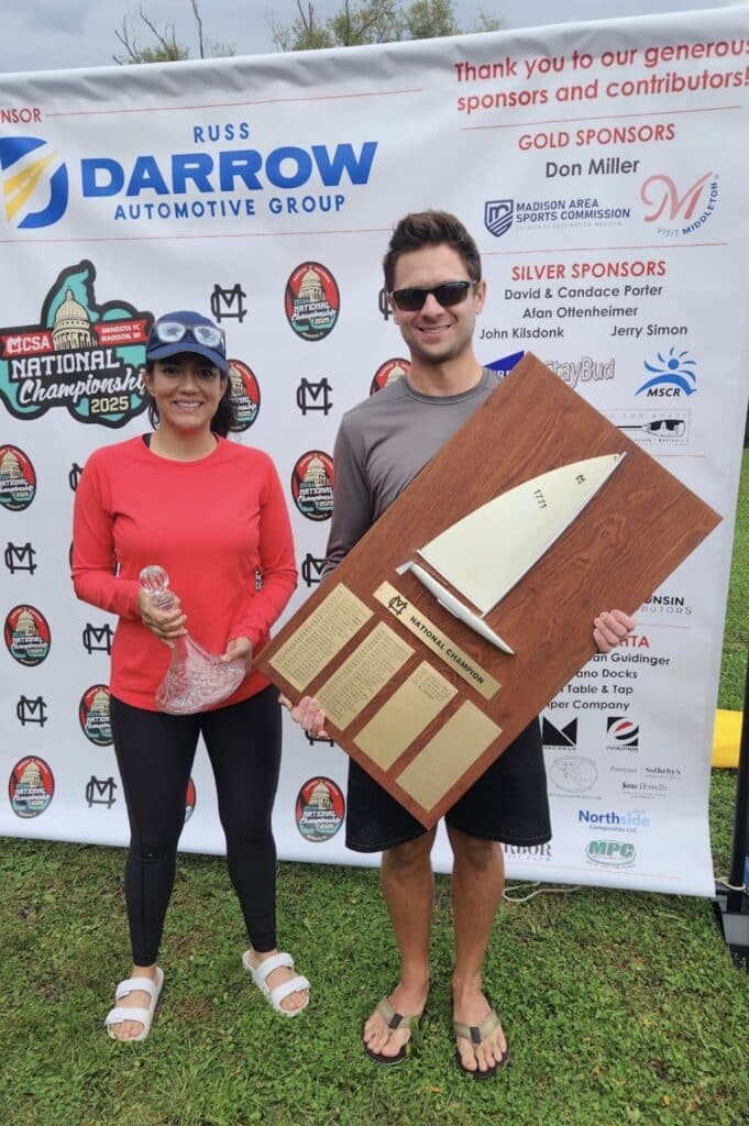 MC Scow Nationals winners holding a trophy in front of the 2025 MCSA Championship sponsor banner